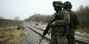 Zwei Soldaten an einem Bahngleis.