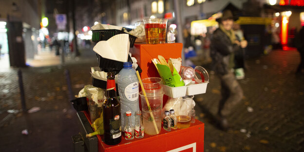Abfall türmt sich auf einem Mülleimer in der Kölner Altstadt