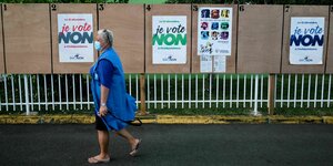 Frau vor Tafel mit Wahlwerbung