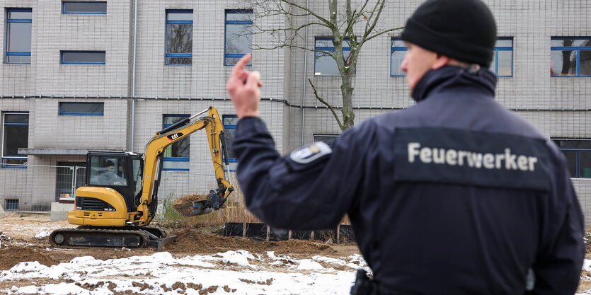 Ein Polizist steht vor einem Bagger