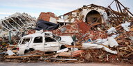 Ein Haufen Trümmer und ein kaputtes Auto stapeln sich vor einem zerstörten Gebäude