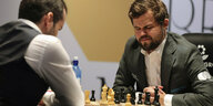 Zwei Schachspieler, Jan Nepomnjaschtschi und Magnus Carlsen, sitzen am Brett.