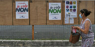 Eine Frau geht an drei Plakaten vorbei, auf denen verschiedene Organisationen zum "Nein"-Wählen aufrufen