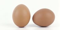 ein stehendes und ein liegendes braunes Ei