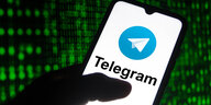 Jemand hält ein Smartpone in der Hand mit Telegram-Logo