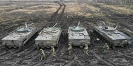 4 russische Panzer im Matsch, davor und dahinter Soldaten