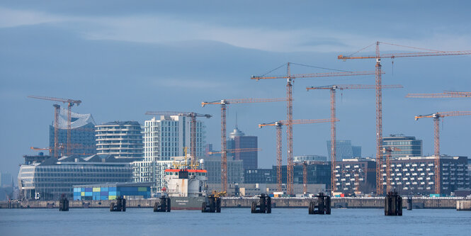 Skyline mit Hochhäusern und Kränen, davor die Elbe mit Duckdalben