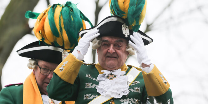 NRW-Innenminister Herbert Reul (r, CDU) steht mit Domprobst Gerd Bachner beim Rosenmontagszug auf einem Wagen.