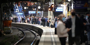 Reisende warten im Hamburger Hauptbahnhof auf einen Zug.
