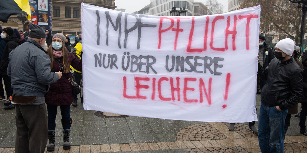 Teilnehmer einer Demonstration gegen Corona-Regelungen tragen ein Plakat mit derAufschrift "Impf-Pflicht nur über unsere Leiche".