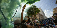 Eine Frau protestiert im grünen Rauch