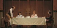 Ein Mann und drei Frauen sitzen an einer Tafel und essen Mittag: Szenenfoto aus der Oper "Katja Kabanowa" an der Komische Oper Berlin