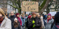 Frauen, Männer und Kinder in winterlicher Kleidung mit handgeschriebenen Plakaten "Corona Diktatur"