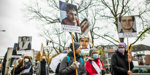 Bei einer Demonstration halten Menschen Tafeln mit Fotos von NSU Opfern hoch