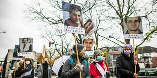 Bei einer Demonstration halten Menschen Tafeln mit Fotos von NSU Opfern hoch