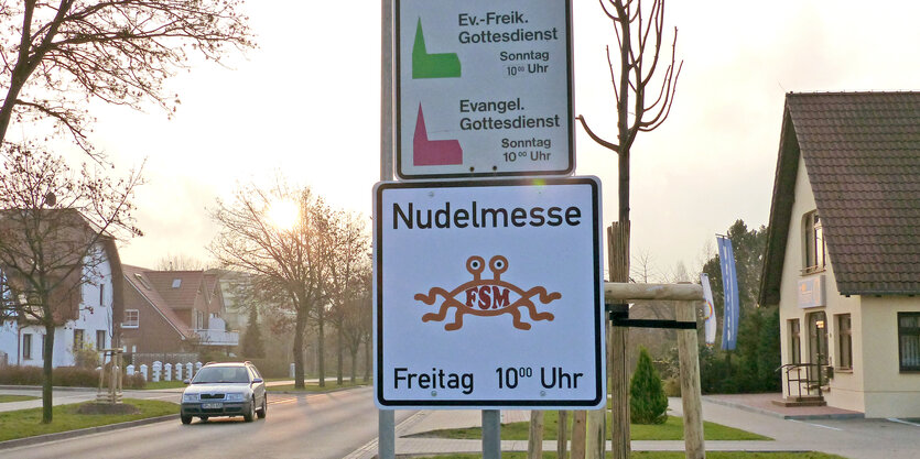 Ein Schild der Spaghettimonster-Kirche an einem Straßenmast