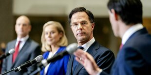 Mark Rutte mit Koalitionspartner auf einer Bühne mit Mikrofone