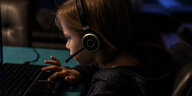 Mädchen mit Kopfhörer tippt auf PC-Tastatur