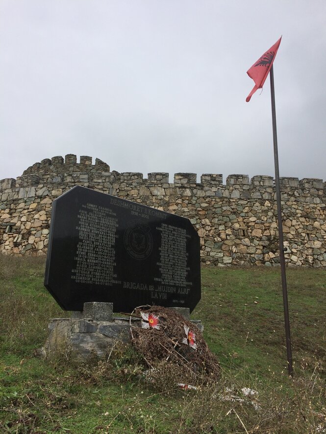 Ein schwarzer Gedenkstein vor einer Festung