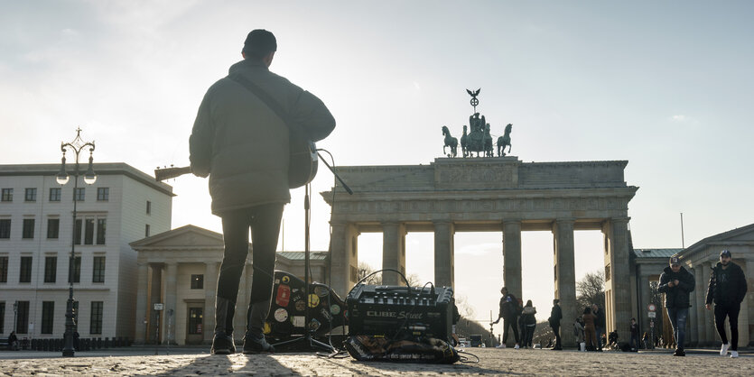 EIn Strassenmusiker spielt vor dem Brandeburgertor Gitarre