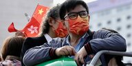 Mann mit roter Maske und Fähnchen von Hongkong und China.