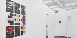 Sicht in die Räume der Galerie Barbara Weiss: die Zwischenwände sind in einer Sternenformation angeordnet, links an der Wand hängt ein Arbeit aus vielen kleinen Quadraten, auf der das Wort "Revolution" zu lesen ist