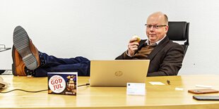 Stefan Seidler legt die Füsse auf den Schreibtisch und hat einen Apfel in der Hand