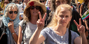 Mehrere Personen zeigen ein Victoryzeichen auf einer Demonstration gegen die Coronamaßnahmen.