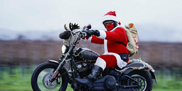 Der Weihnachtsmann sitzt auf einem Motorad.