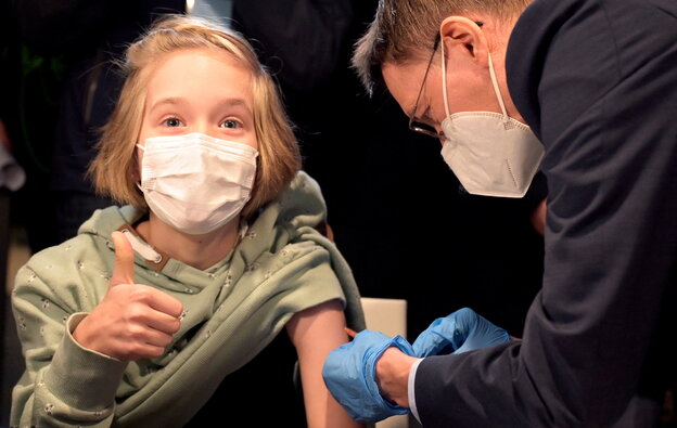 GesundheitsministerLauterbach impft ein Kind, das den Daumen hoch zeigt.
