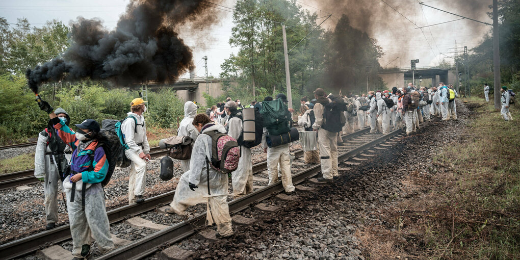 Gleisbesetzung von Aktivist*innen in weißen Anzügen.