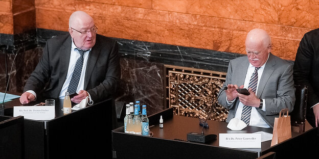 Die Anwälte Thomas Fischer und Peter Gauweiler sitzen vor einer Marmorwand im Festsaal des Hamburger Rathauses