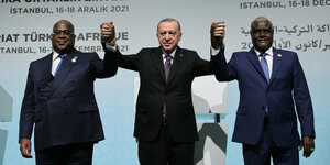 Recep Tayyip Erdogan hält die Händer zweier Männer in die Höhe