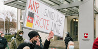 Eine Menschengruppe vor der niedrsächsischen Staatskanzlei, eine trägt ein Schild mit der Aufschrift: "Wir sind die rote Linie. Freie Niedersachsen"