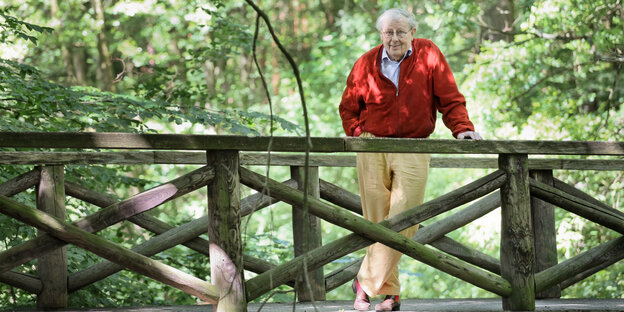 Klaus Wagenbach, ein älterer Herr im roten Pullover, steht an einem Geländer im Wald