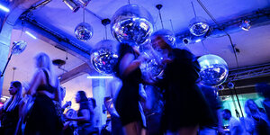 Dutzende Menschen tanzen zur Musik unter Discokugeln