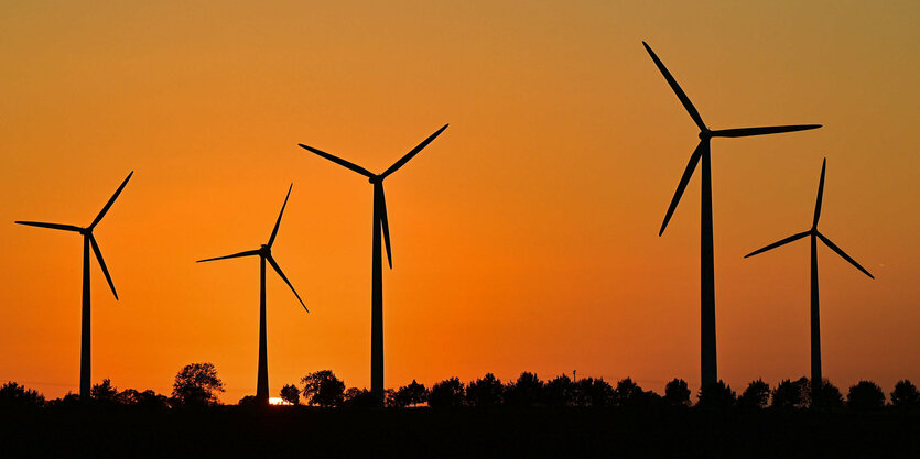 Windräder vor einem Sonnenuntergang.