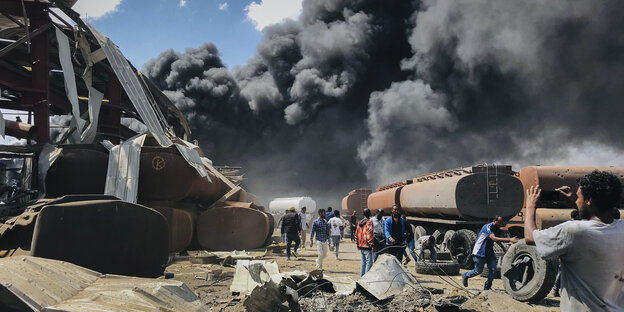 Menschen stehen nach einem Luftangriff auf die Hauptstadt der Region Tigray im Norden Äthiopiens vor schwarzen Rauchschwaden