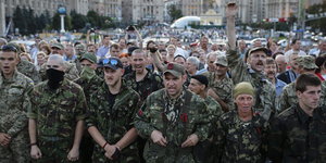 Männer und Frauen in Uniformen und teilweise vermummt demonstrieren auf dem Maidan