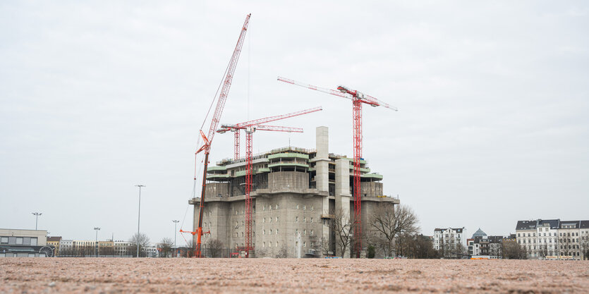 Mehrere Kräne stehen rund um einen Bunker auf einem großen leeren Platz