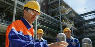 Robert Habeck im Schutzanzug mit Brille und Helm hält eine Ampulle