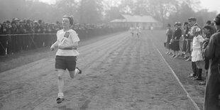 Leichtathletin auf einer von Zuschauern umsäumten Aschenbahn in England