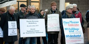 Menschen mit umgehängten Plakaten stehen nebeneinander