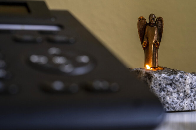 Ein Engel mit Kerze steht hinter einem Telefonapparat