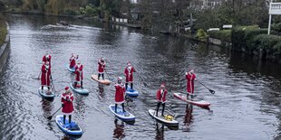 Gruppe von zehen Frauen und Männern als Nikolause verkleidet beim Stand Up-Paddeln auf der Alster in Hamburg