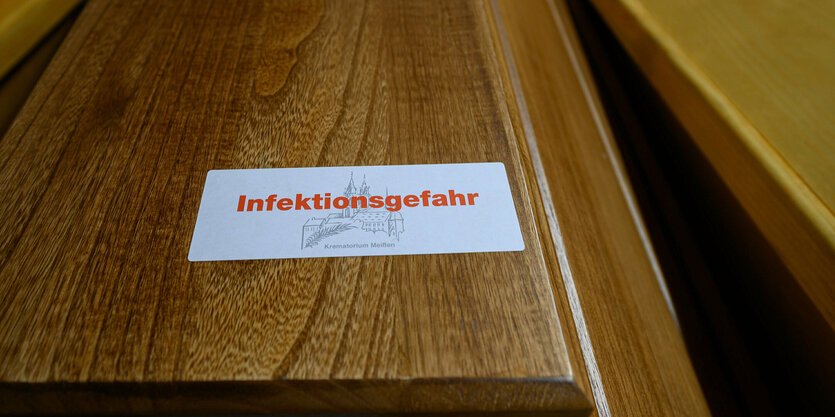 Sarg aus Holz mit Aufschrift "Infektionsgefahr"