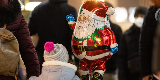 Ein Kind hält einen Weihnachtsmann-Ballon. Kurz vor Weihnachten ist die Frankfurter Einkaufsstraße Zeil voll mit Menschen