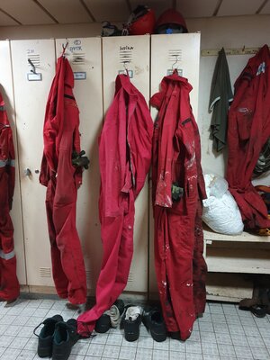 Eine Umkleidekabine, in der rote Overalls hängen Eine Umkleidekabine, in der rote Overalls hängen
