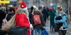 in Reisender im Weihnachtsmann-Kostüm steht zur Hauptreisezeit vor Weihnachten am Hauptbahnhof.
