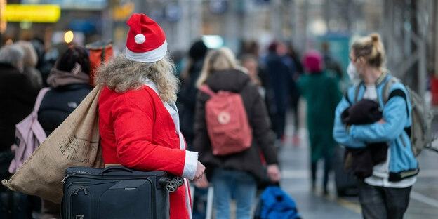 in Reisender im Weihnachtsmann-Kostüm steht zur Hauptreisezeit vor Weihnachten am Hauptbahnhof.